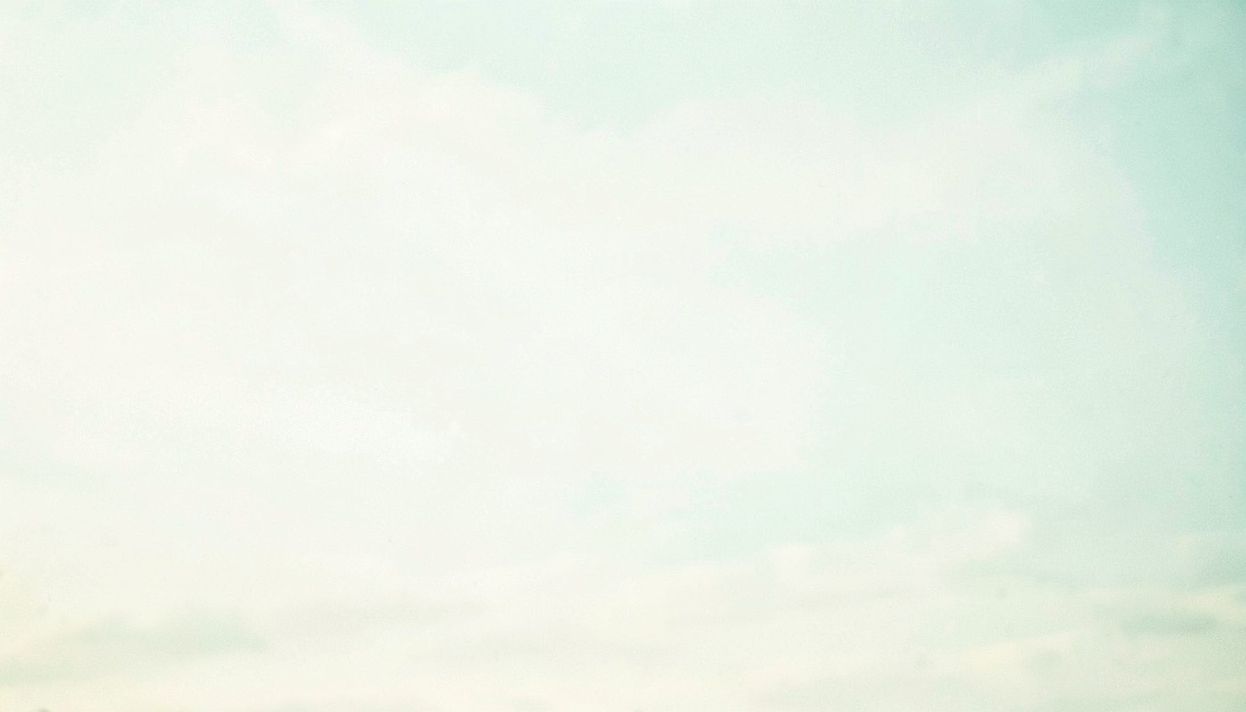 A bright, airy photograph of an open horizon with soft pale light, in muted teal and cream tones.